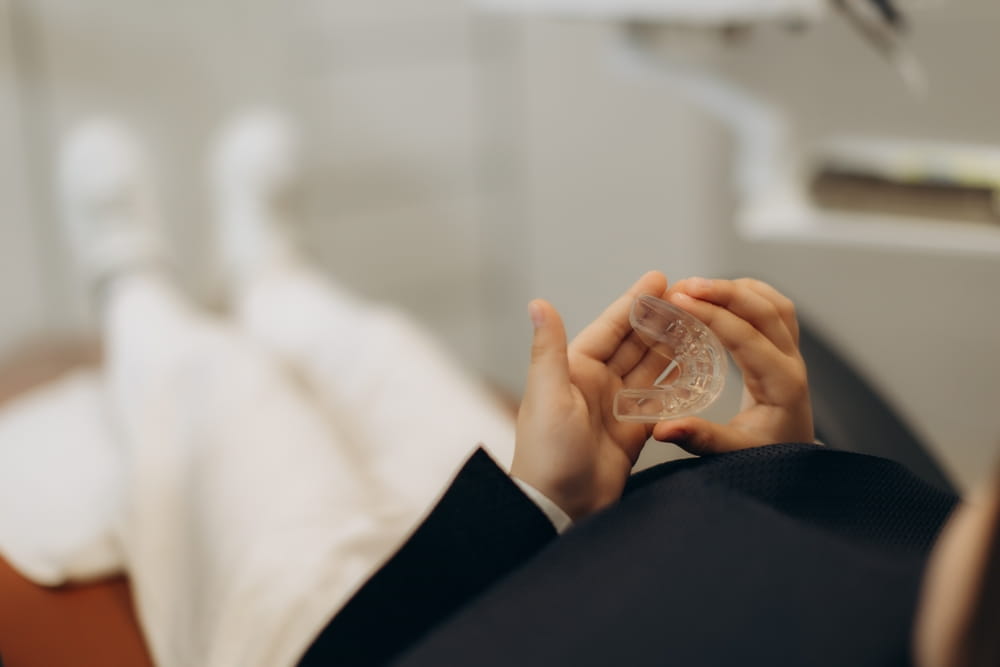 Une patiente tient dans ses mains une plaque occlusale contre le bruxisme